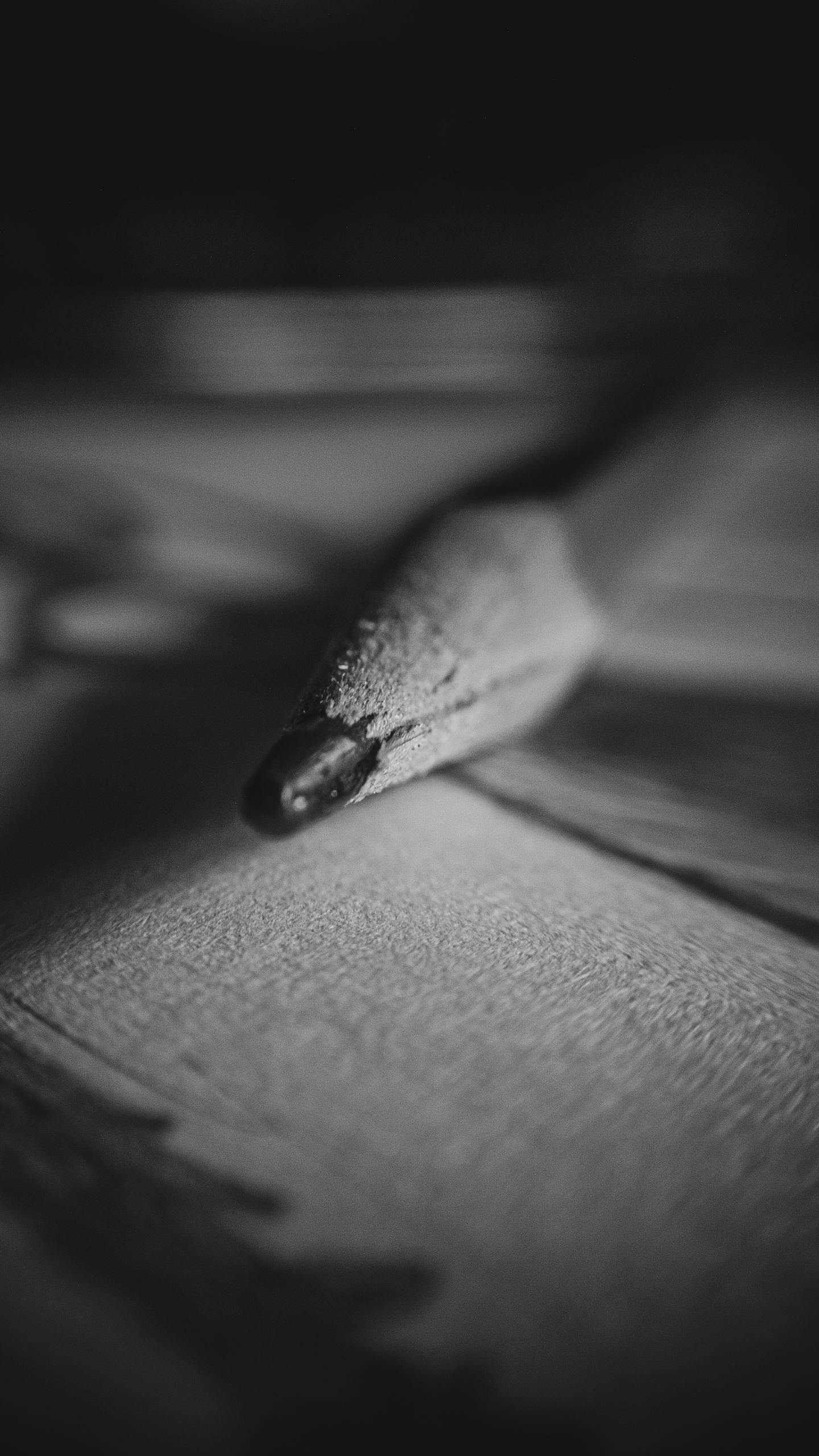 Monochromatyczne zbliżenie końcówki ołówka na papierze, podkreślające fakturę i artystyczne detale.
