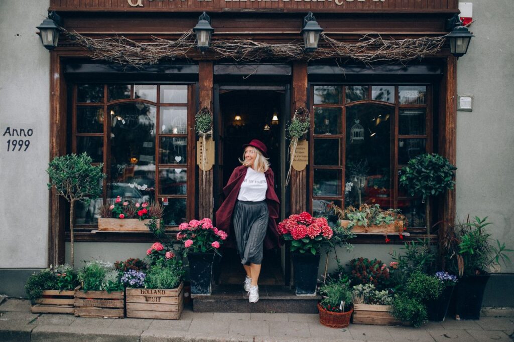pexels-photo-4813828-4813828 Stylish woman in red hat outside a flower shop surrounded by vibrant autumn flowers.
